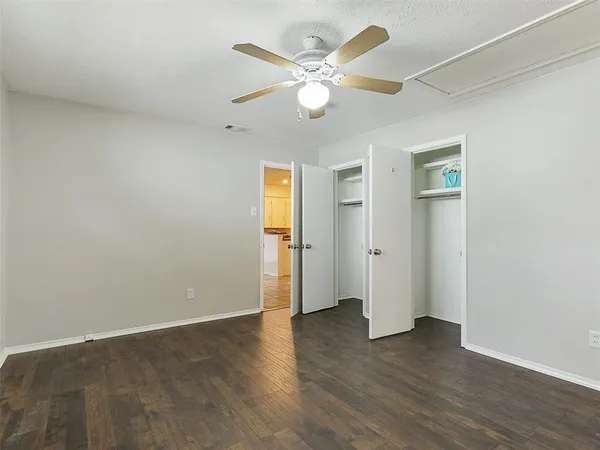 an empty room with wooden floor and ceiling fan