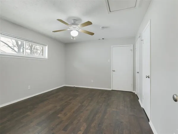 an empty room with wooden floor fan and windows
