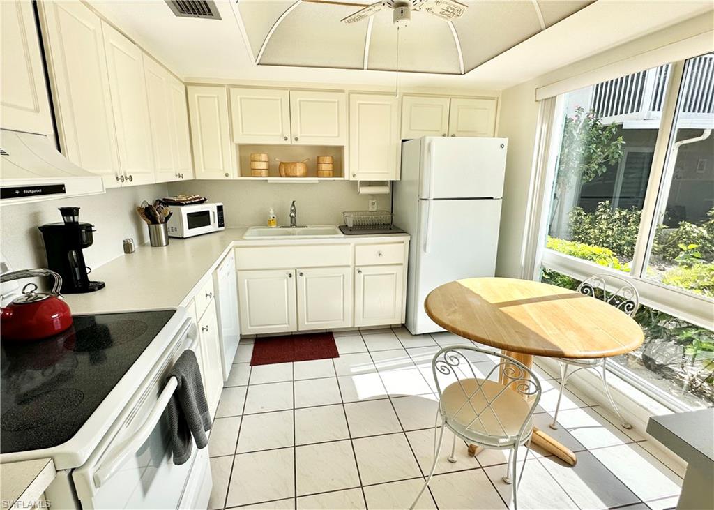 a kitchen with a sink a stove a refrigerator and white cabinets with wooden floor