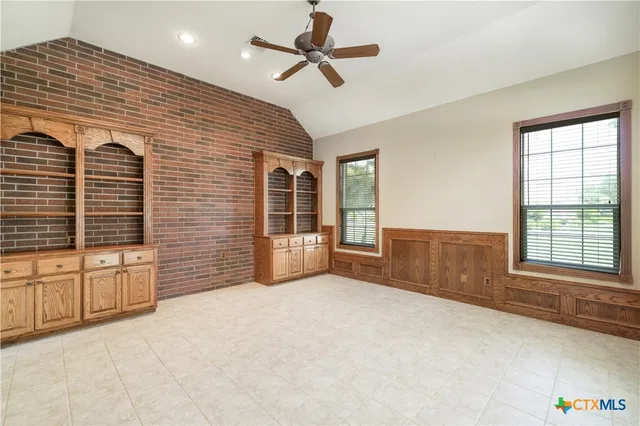 a view of an empty room with a window and a kitchen
