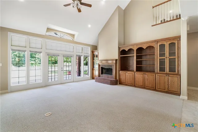 a view of an empty room with a window and a kitchen