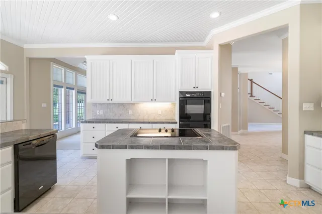 a kitchen with granite countertop white cabinets and stainless steel appliances