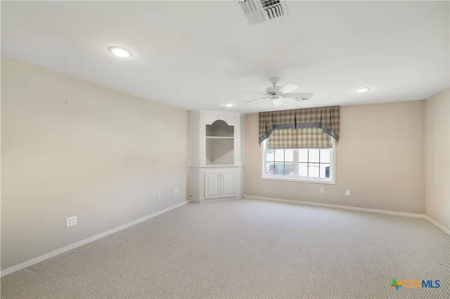 an empty room with windows and chandelier fan