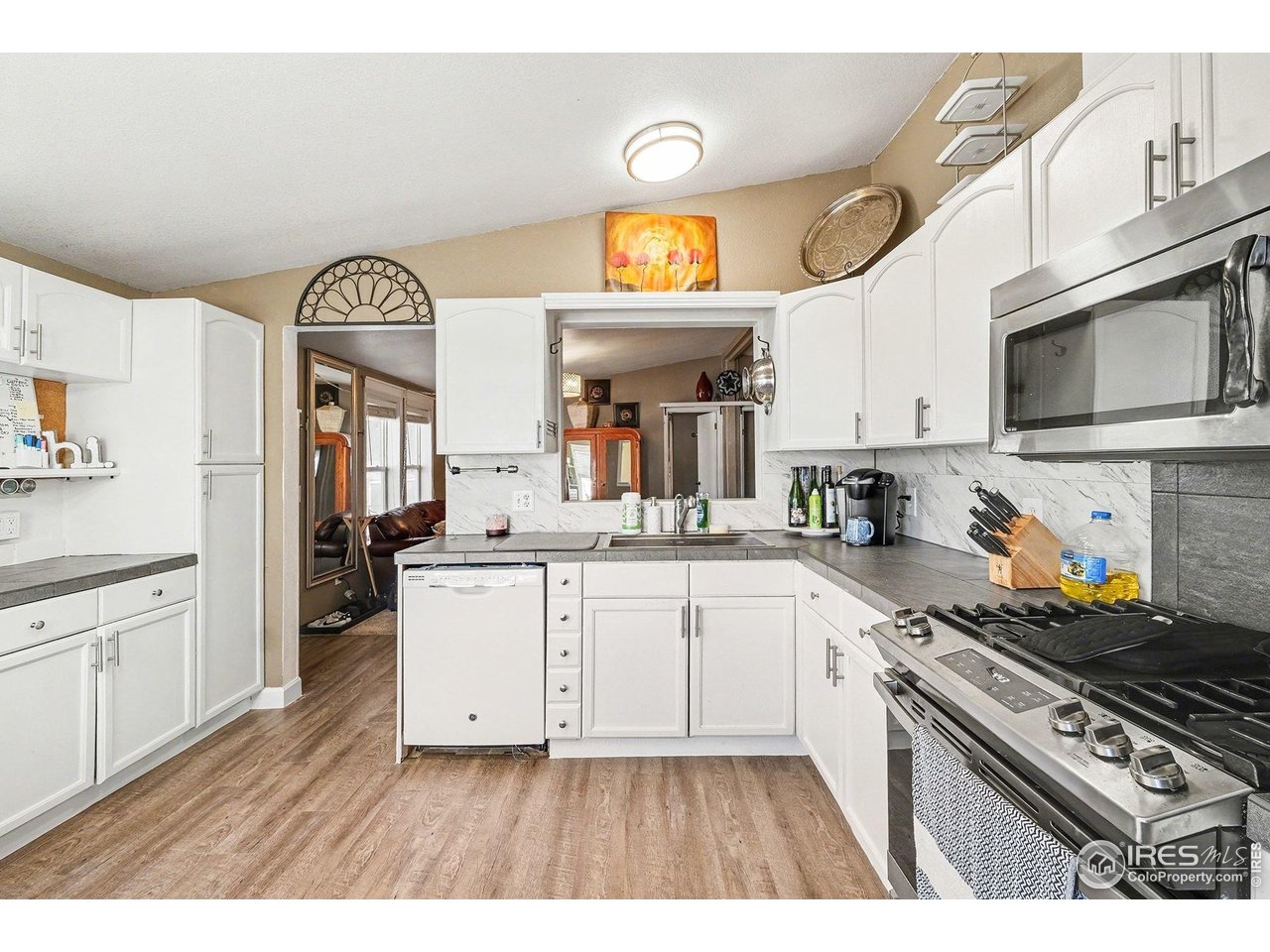 2500 East Harmony Road, Unit 269 Fort Collins, CO 80528 - Photo 7 of 22 a kitchen with stainless steel appliances granite countertop a stove a sink dishwasher and white cabinets with wooden floor
