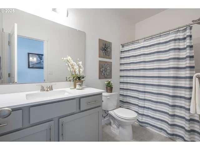 a bathroom with a sink a toilet a mirror and shower curtain