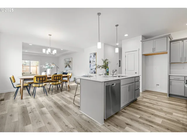 a kitchen with stainless steel appliances kitchen island granite countertop a table chairs and a refrigerator