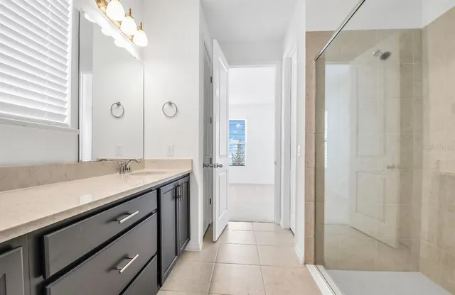 a bathroom with a granite countertop sink a mirror and a shower