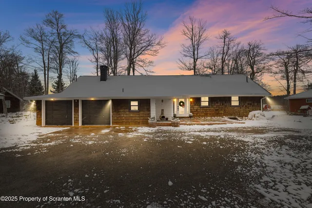 a front view of a house with a yard covered in snow
