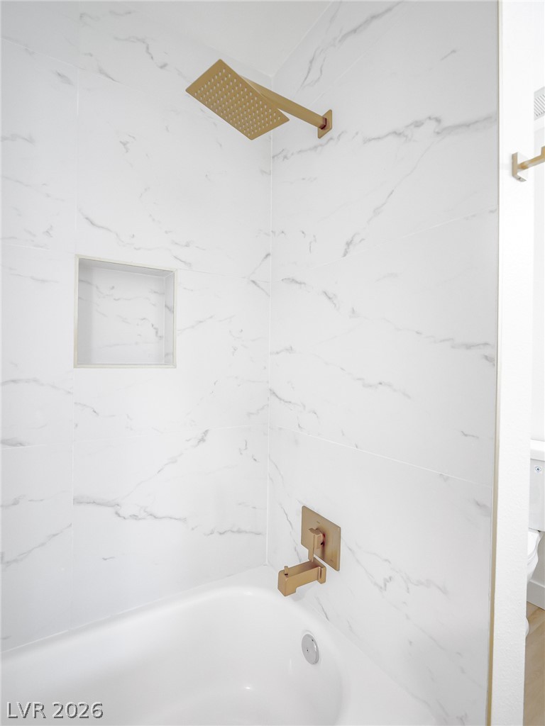 321 Lakehurst Road Las Vegas, NV 89145 - Photo 18 of 33 Elegant stone-look tile surrounds the built-in tub paired with contemporary gold fixtures.