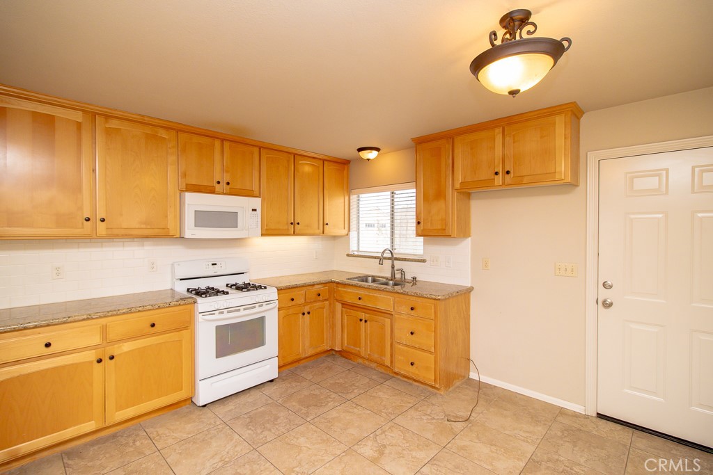 20376 Tonawanda Road Apple Valley, CA 92307 - Photo 54 of 67 a kitchen with stainless steel appliances granite countertop a stove a sink dishwasher and a refrigerator with wooden floor