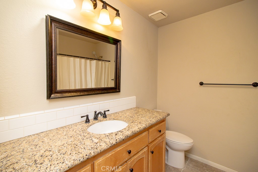 20376 Tonawanda Road Apple Valley, CA 92307 - Photo 63 of 67 a bathroom with a granite countertop sink toilet and mirror