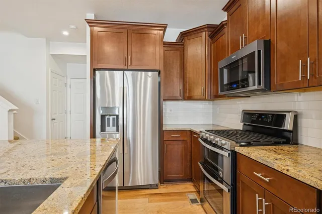 a kitchen with stainless steel appliances kitchen island granite countertop a sink and a refrigerator