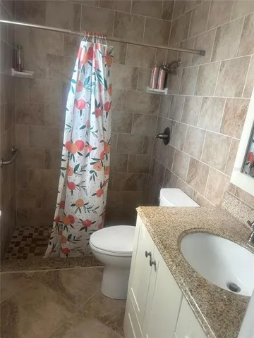 a bathroom with a granite countertop sink a toilet and shower