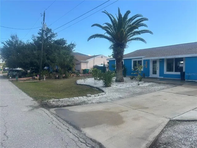 a view of a house with a yard and palm trees