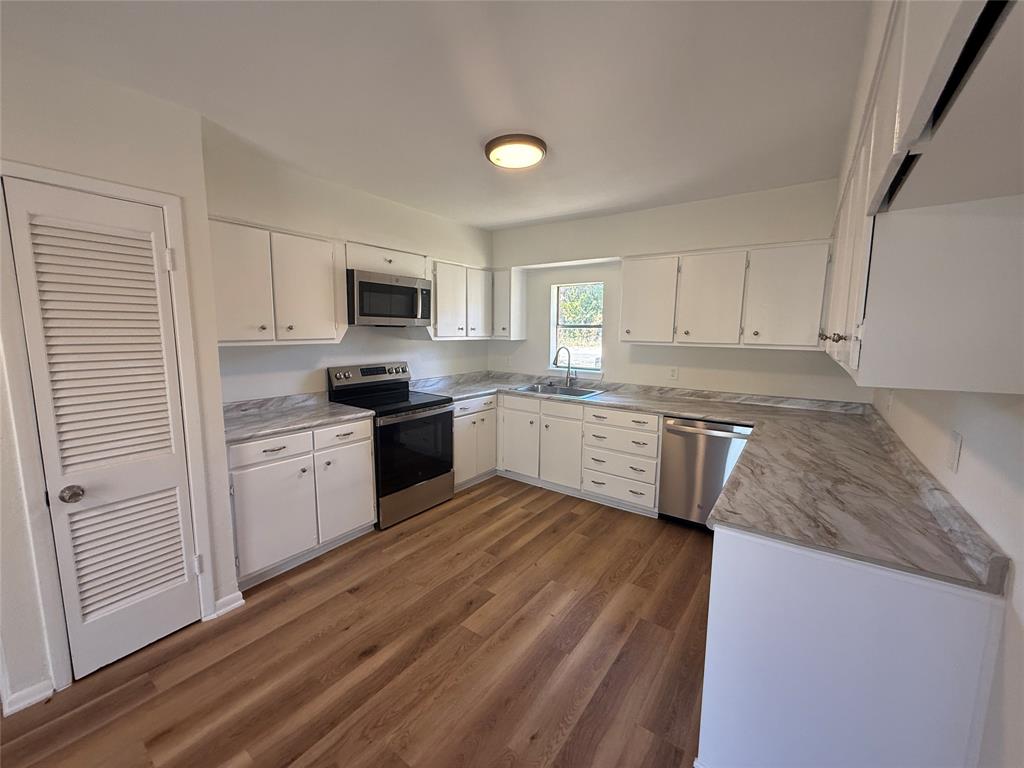 1102 Chilton Street Weatherford, TX 76086 - Photo 6 of 28 a kitchen with granite countertop white cabinets and white appliances