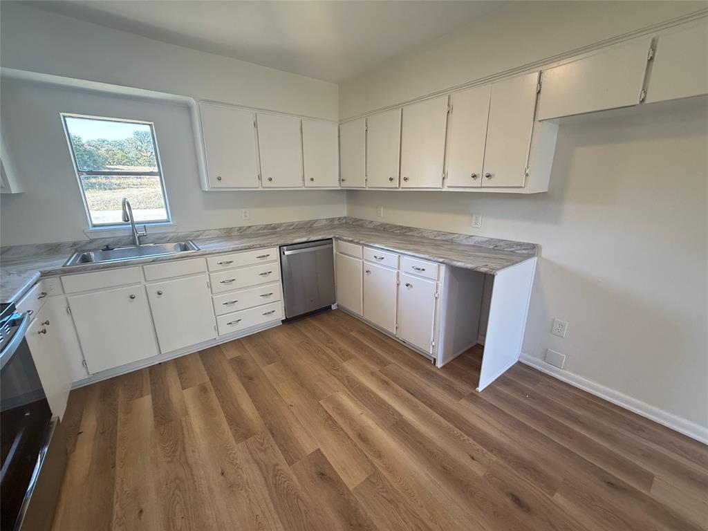 1102 Chilton Street Weatherford, TX 76086 - Photo 7 of 28 a kitchen with granite countertop white cabinets white appliances a sink and a window