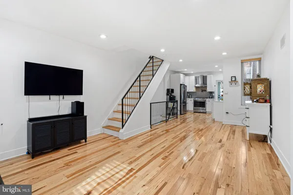 a view of a living room with wooden floor and a flat screen tv