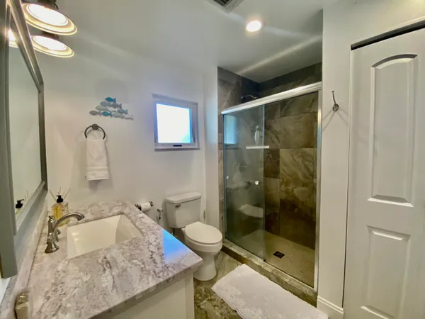 a bathroom with a granite countertop sink a toilet and shower