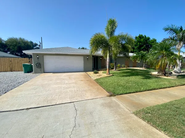 a view of a house with a yard and palm trees