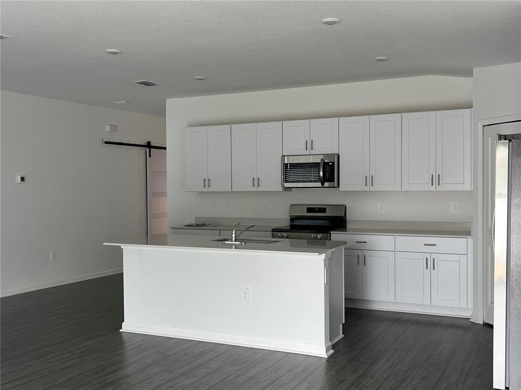 4576 Southwest 84th St Road Ocala, FL 34476 - Photo 13 of 50 a kitchen with stainless steel appliances granite countertop a sink a stove a microwave and cabinetry