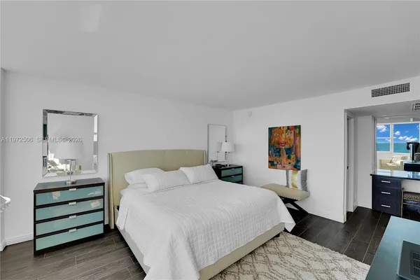 a bedroom with a bed wooden floor and large window