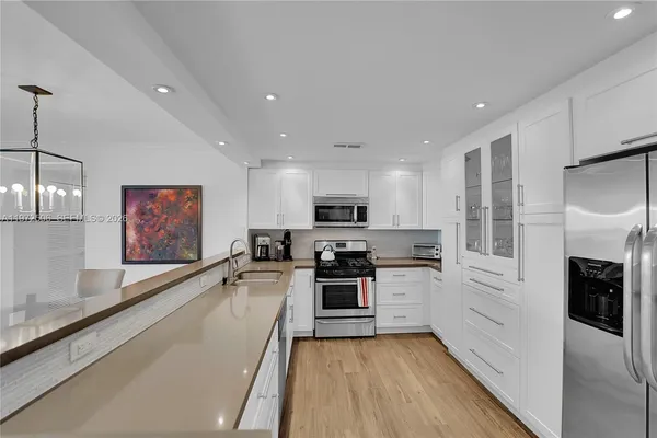 a large kitchen with stainless steel appliances granite countertop a large counter top a stove a sink and a refrigerator