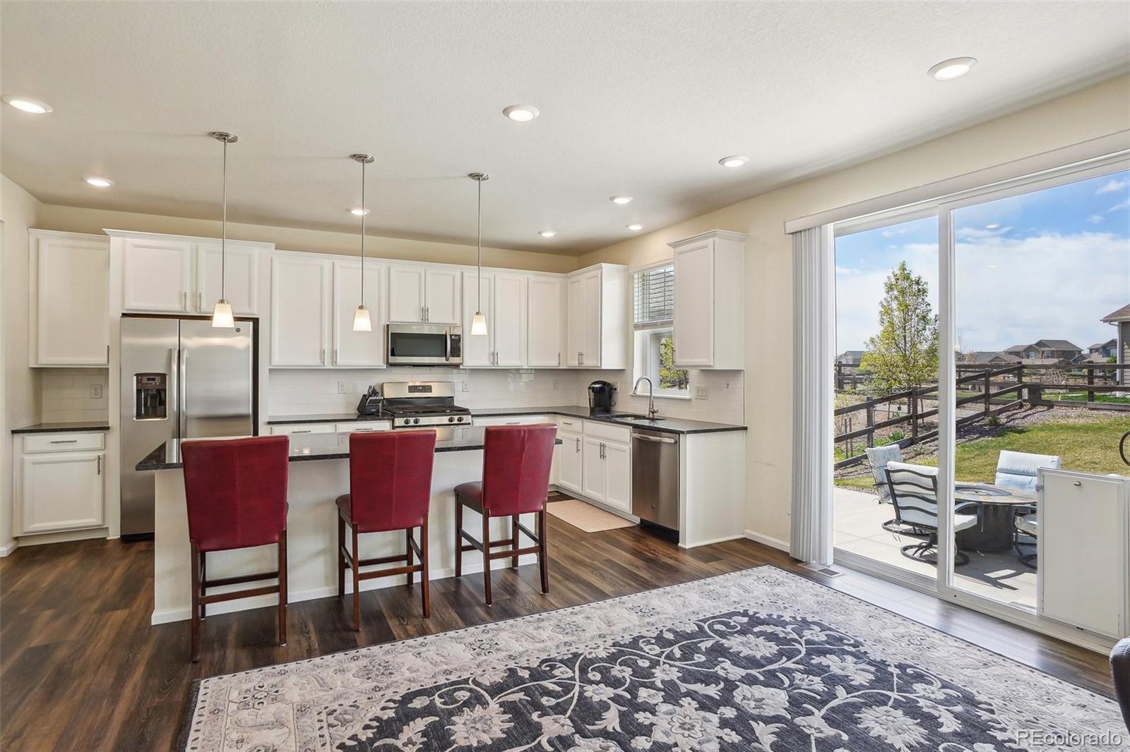12797 Clearview Street Firestone, CO 80504 - Photo 3 of 44 a kitchen with stainless steel appliances granite countertop a stove a refrigerator a kitchen island a dining table and chairs with wooden floor