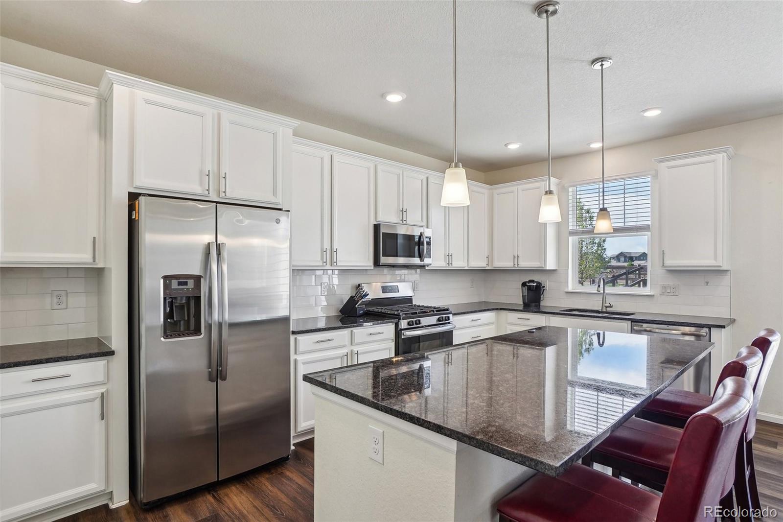12797 Clearview Street Firestone, CO 80504 - Photo 5 of 44 a kitchen with stainless steel appliances granite countertop a refrigerator a sink a stove a dining table and chairs