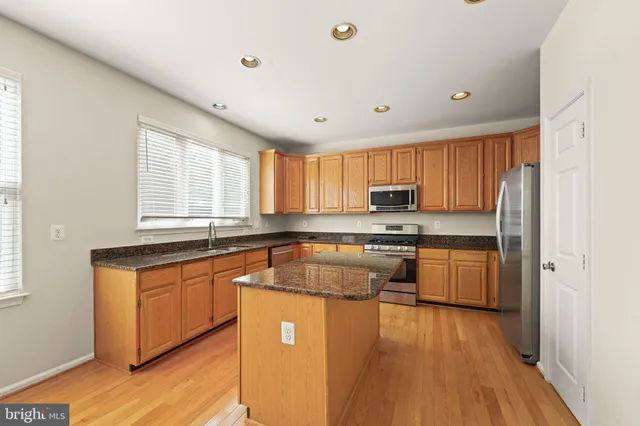 a kitchen with stainless steel appliances granite countertop a sink a stove and a refrigerator