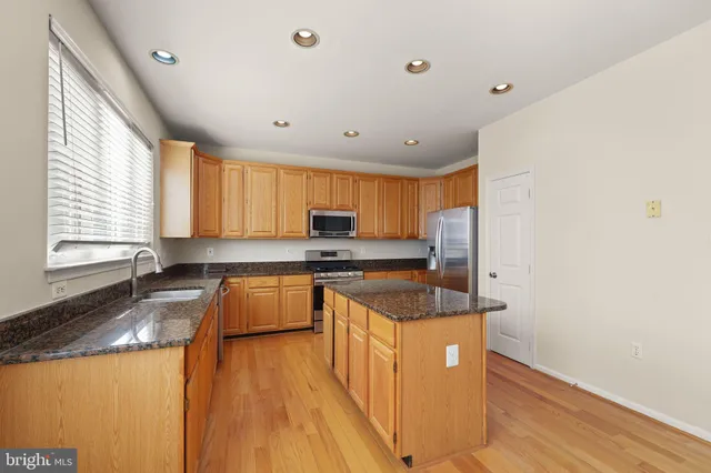 a kitchen with granite countertop a sink a counter space appliances and windows