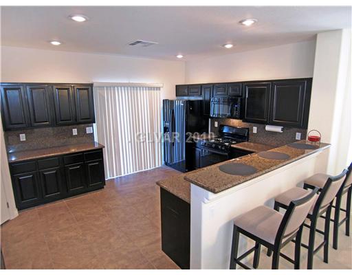 1348 Spice Ridge Court Henderson, NV 89012 - Photo 3 of 8 Kitchen. Rich dark cherry cabinets with 3/4" charcoal speckled granite counters and back splashes, breakfast/serving bar, built-in microwave and 9-month old upgraded refrigerator.