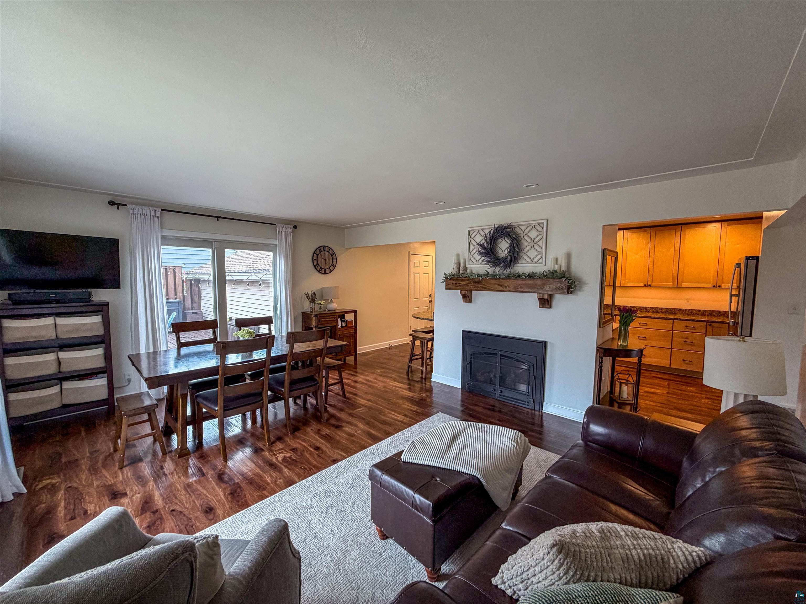 3704 Greysolon Road Duluth, MN 55804 - Photo 2 of 51 Spacious living area featuring wood-finish flooring, a fireplace with a wood mantle, and a sliding glass door
