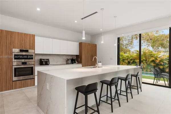 a kitchen with kitchen island a stove a table and chairs in it