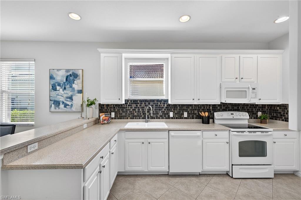 14088 Mirror Court Naples, FL 34114 - Photo 11 of 31 Kitchen featuring white appliances, white cabinets, a peninsula, recessed lighting, and tasteful backsplash