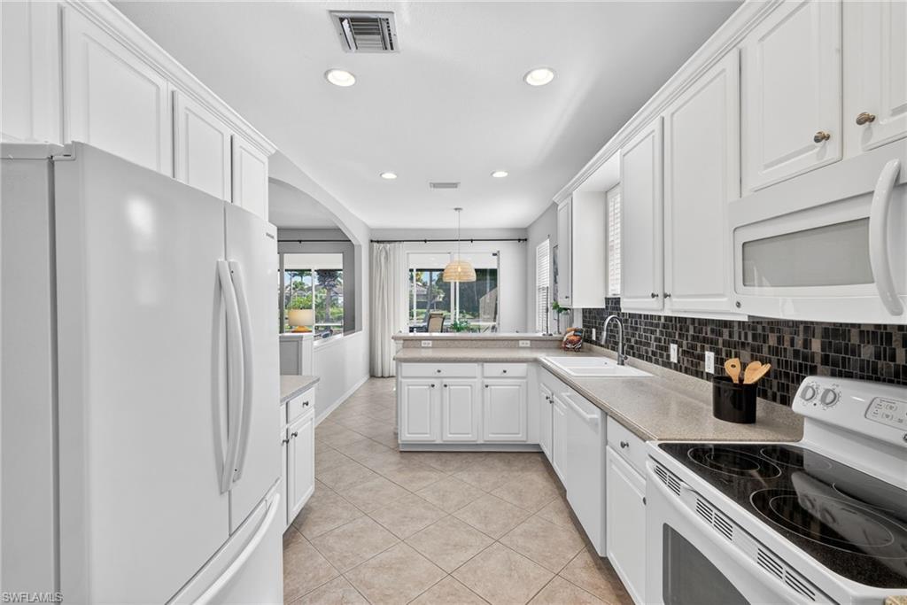 14088 Mirror Court Naples, FL 34114 - Photo 12 of 31 Kitchen with white appliances, white cabinets, recessed lighting, light tile patterned floors, and decorative backsplash