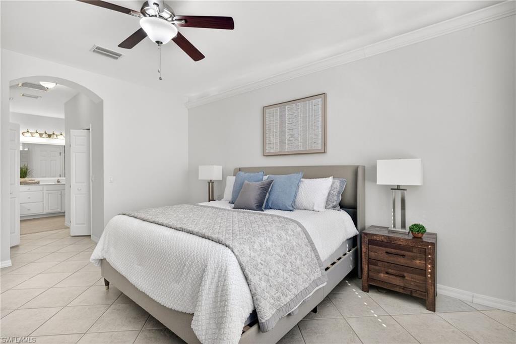 14088 Mirror Court Naples, FL 34114 - Photo 15 of 31 Primary Bedroom with arched walkways, light tile patterned floors, ensuite bathroom, and ceiling fan
