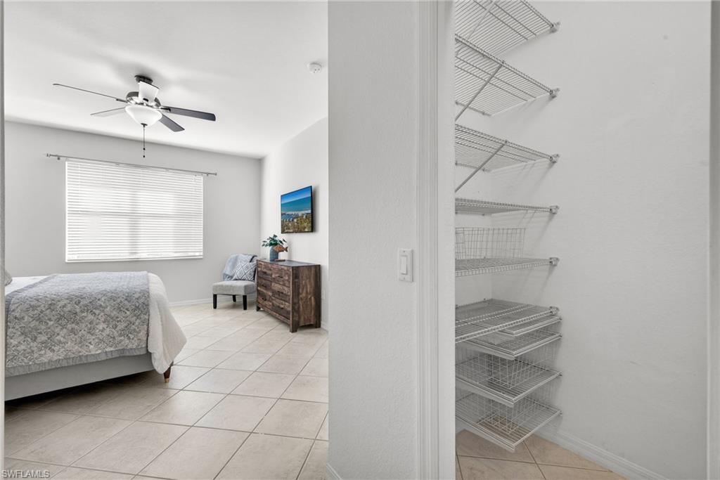 14088 Mirror Court Naples, FL 34114 - Photo 20 of 31 Primary Bedroom featuring 2 walk-in closets with built in shelving/storage light tile patterned flooring