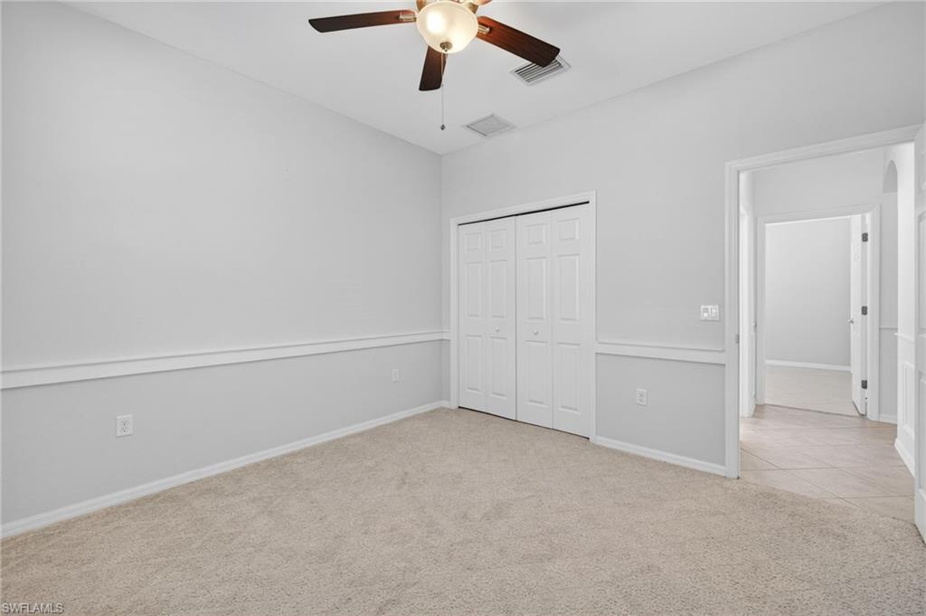 14088 Mirror Court Naples, FL 34114 - Photo 22 of 31 Bedroom 3 featuring light colored carpet, wainscotting a ceiling fan, and closet