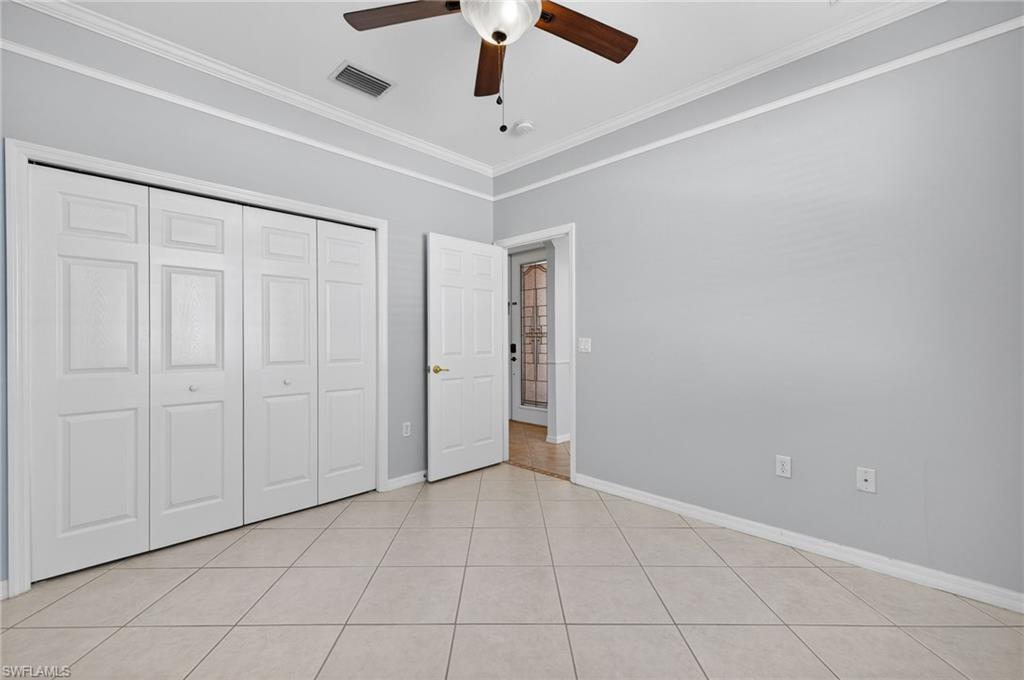 14088 Mirror Court Naples, FL 34114 - Photo 25 of 31 Bedroom 2 featuring decorative molding, a ceiling fan, a closet, and light tile patterned floors