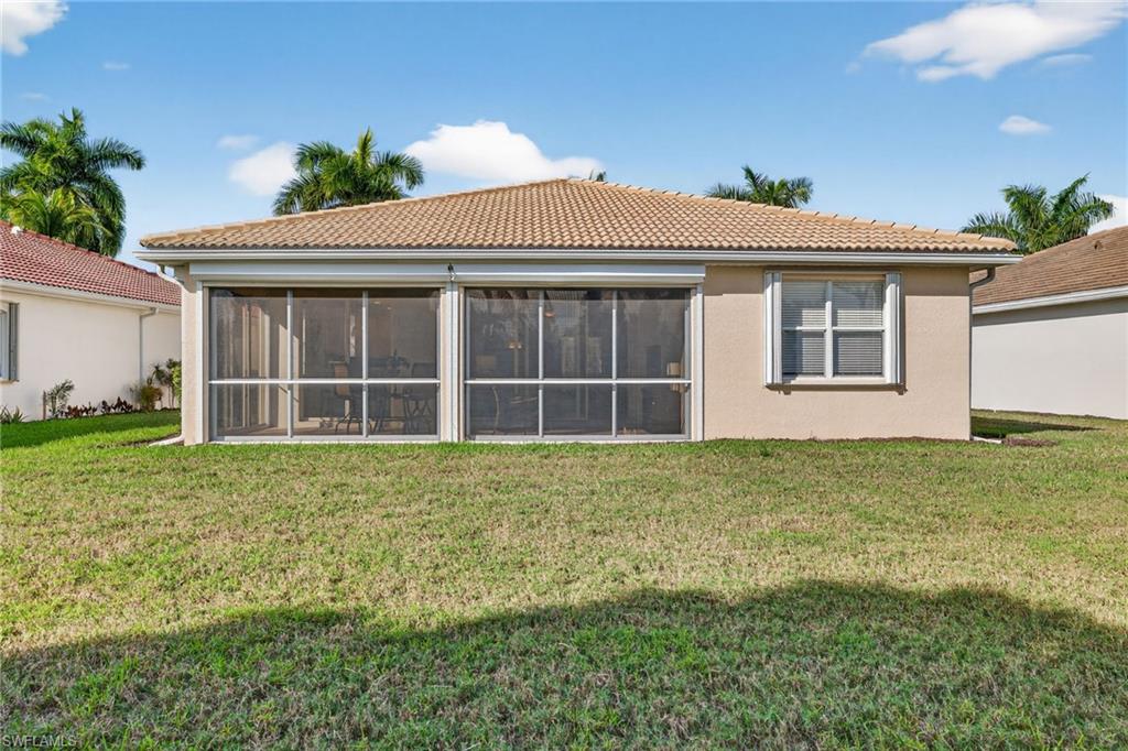 14088 Mirror Court Naples, FL 34114 - Photo 30 of 31 Rear view of property featuring a tiled roof, a yard, and stucco siding