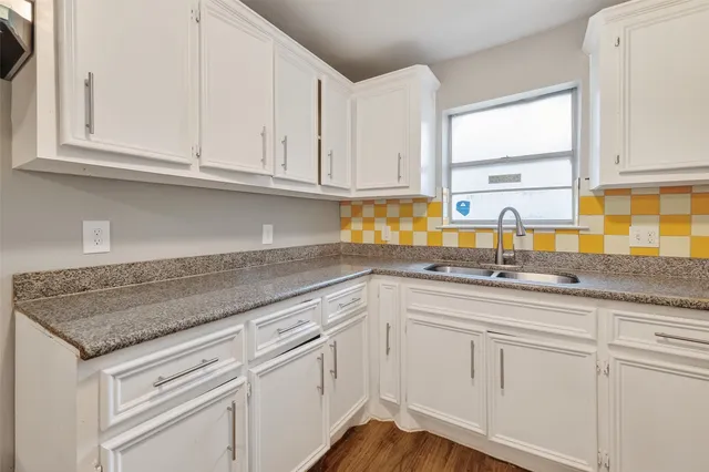 a kitchen with granite countertop white cabinets and sink