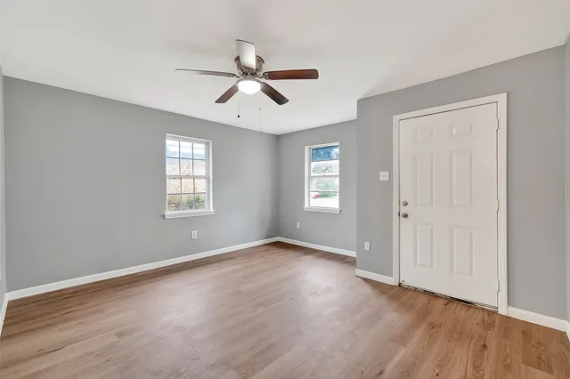 a view of an empty room with a window and wooden floor