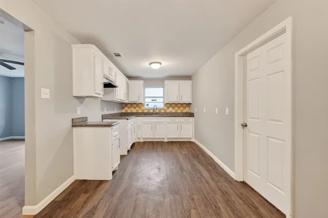 a kitchen with white cabinets and wooden floor