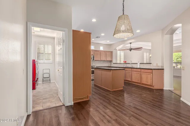 a kitchen with stainless steel appliances granite countertop a refrigerator a sink and white cabinets with wooden floor