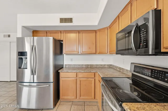 a kitchen with stainless steel appliances granite countertop a refrigerator a sink and a stove