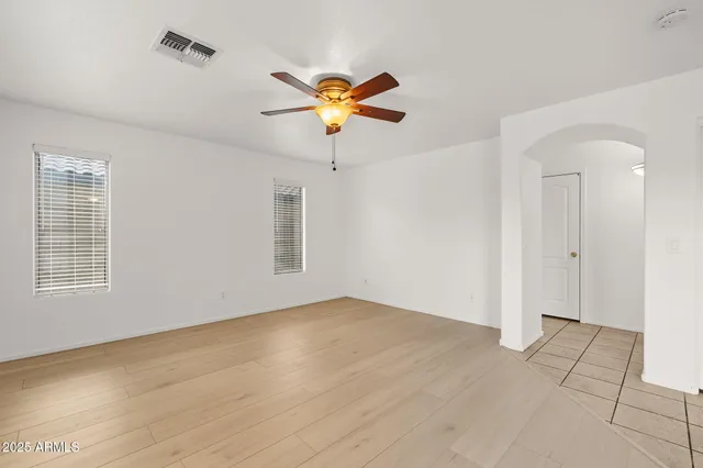 a view of an empty room with chandelier fan and fire place