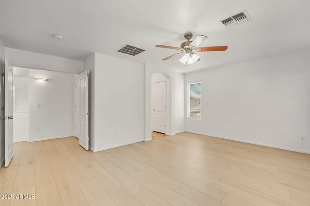 an empty room with windows and ceiling fan