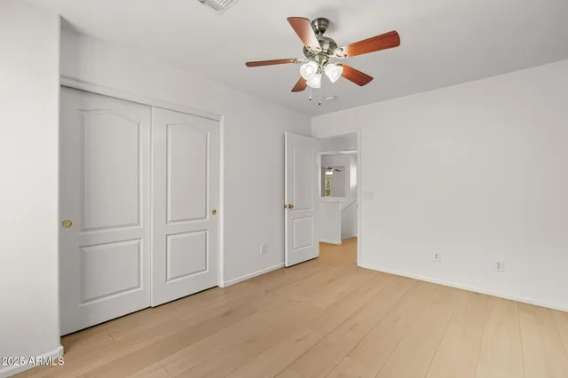an empty room with wooden floor and a ceiling fan