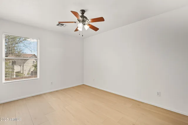 an empty room with a window and a fan