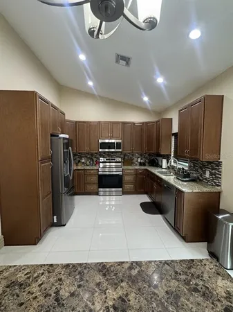 a kitchen with stainless steel appliances granite countertop a refrigerator a stove a sink and a oven